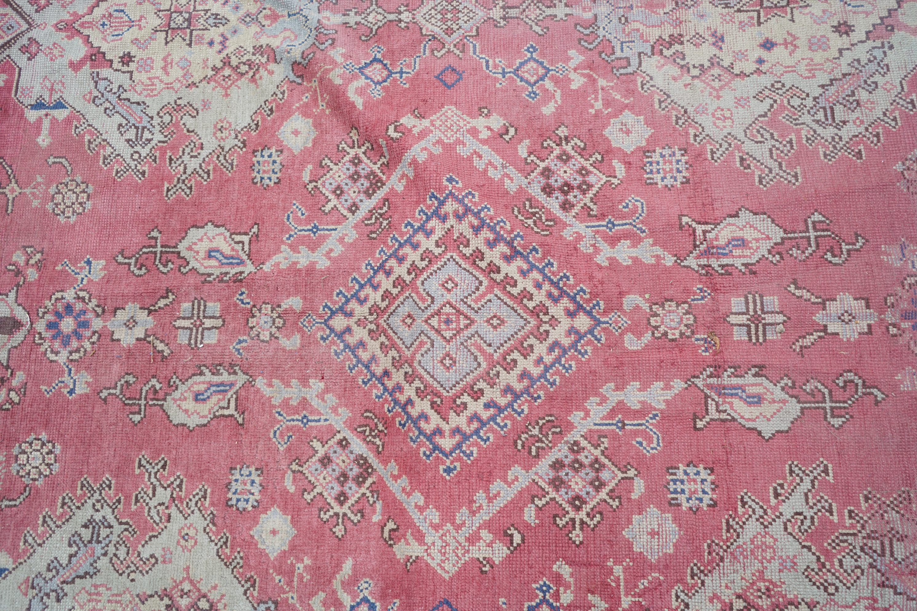 A large Turkish faded red ground carpet